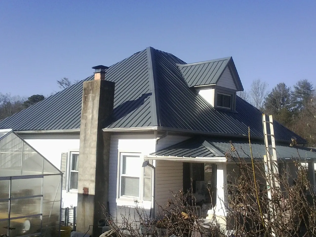 Dark blue standing seam metal roof on a white farmhouse with dormer — Slate & Tile Roof Repair by Roofing Brothers in Boyertown