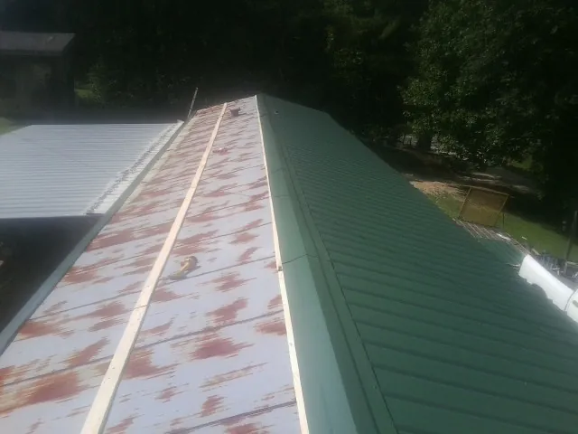 Old rusted panels beside newly installed green metal roofing — Wind Damage Roof Repair by Roofing Brothers in Boyertown