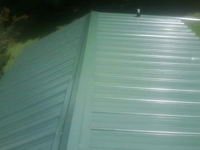 New green metal panels meeting at the ridge of a roof — Flat Roof Repair work by our crew in Boyertown