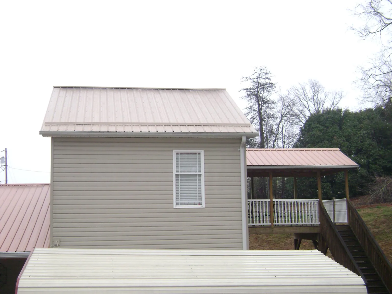 Tan metal roofs on a two story addition and attached porch, from a Roof Replacement job in Boyertown