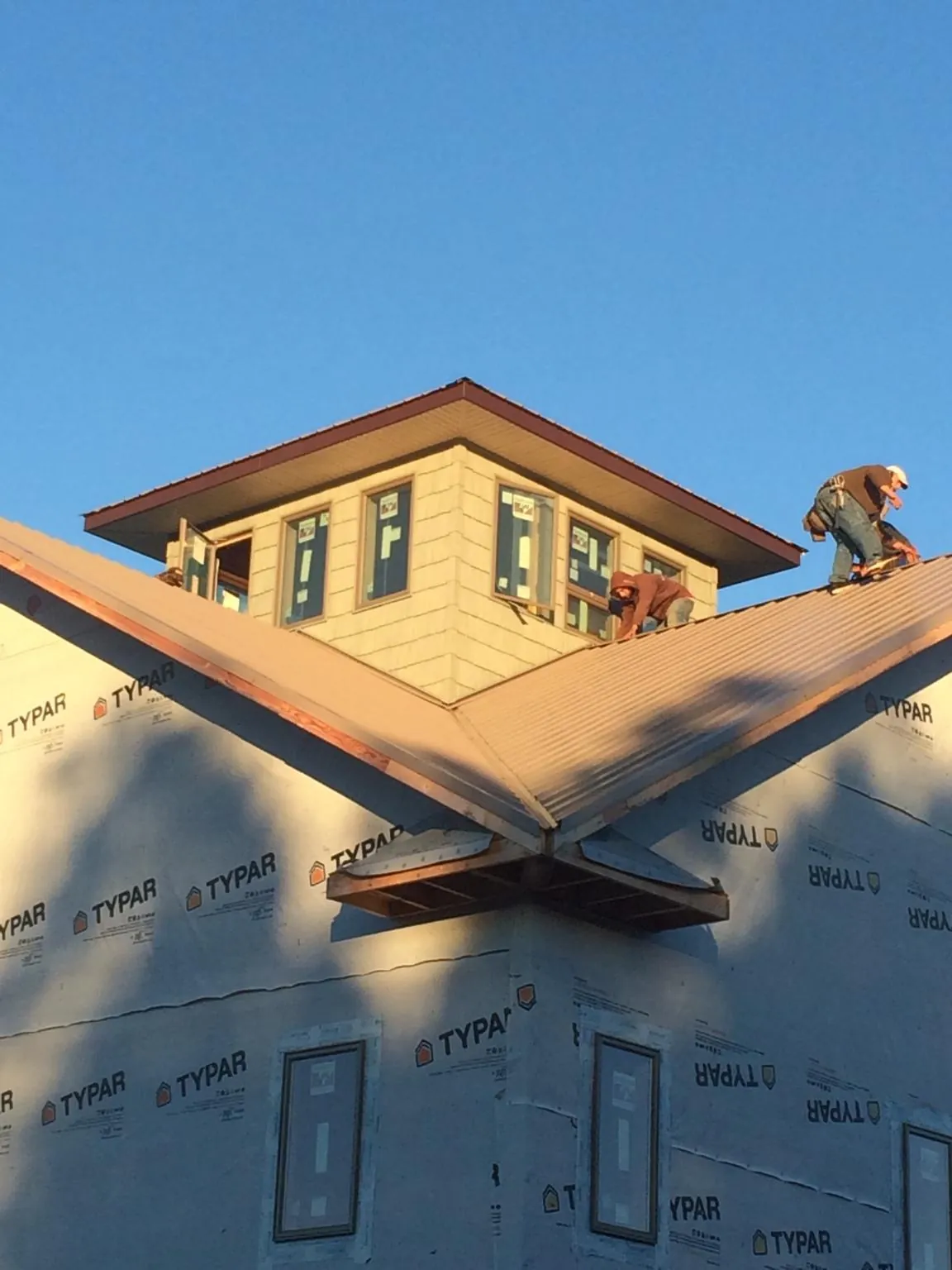 Roofers working around a rooftop cupola on a new metal roof at sunset — Roof Waterproofing in Boyertown by Roofing Brothers